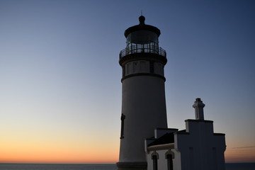 Lighthouse stands along coastal range at dusk.