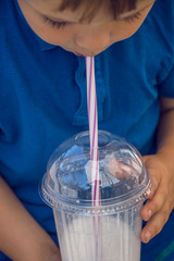 
Little boy drinking milkshake from a plastic cup

