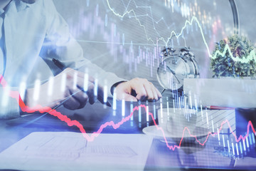 Double exposure of man's hands holding and using a phone and financial graph drawing. Analysis concept.