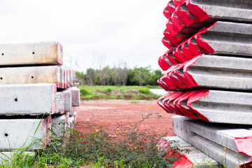 Front and side view of concrete pole pile on ground. Red mark at the end of the pile. Stack of...