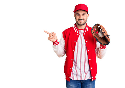 Young handsome man holding baseball gloves smiling happy pointing with hand and finger to the side