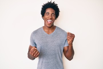 Handsome african american man with afro hair wearing casual clothes celebrating surprised and amazed for success with arms raised and eyes closed