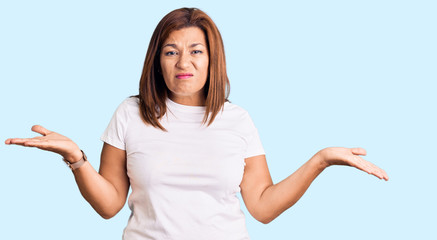 Middle age latin woman wearing casual white tshirt clueless and confused with open arms, no idea...