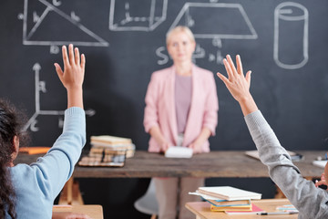 Arms of two clever schoolkids willing to answer question of teacher at lesson