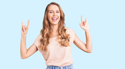 Fototapeta na wymiar Young beautiful caucasian woman with blond hair wearing casual clothes shouting with crazy expression doing rock symbol with hands up. music star. heavy music concept.