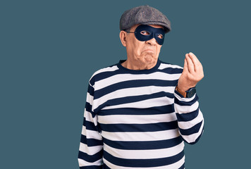 Senior handsome man wearing burglar mask and t-shirt doing italian gesture with hand and fingers confident expression