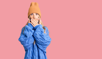 Obraz premium Beautiful caucasian woman with blonde hair wearing wool sweater and winter hat shocked covering mouth with hands for mistake. secret concept.