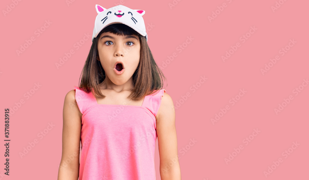 Wall mural Young little girl with bang wearing funny kitty cap scared and amazed with open mouth for surprise, disbelief face - Wall murals