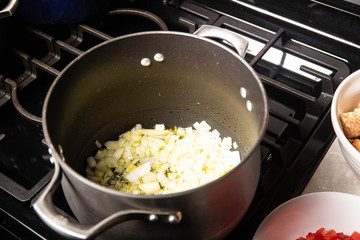 Black pot on stove with oil, onions and garlic preparing a meal