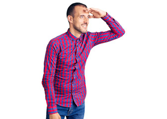 Fototapeta premium Young handsome man wearing casual clothes very happy and smiling looking far away with hand over head. searching concept.