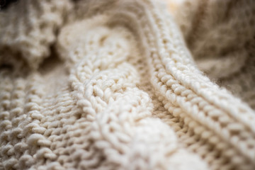 Detail of hand-woven beige wool blanket on wicker chair.
