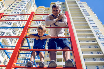 Dad and son on a red children's sports climbing frame
