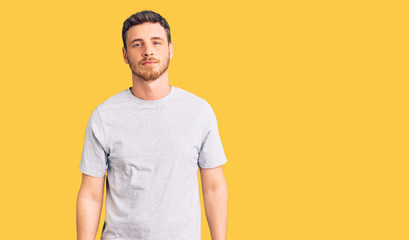 Handsome young man with bear wearing casual tshirt relaxed with serious expression on face. simple and natural looking at the camera.