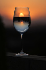 Beautiful reflection of the sky, clouds and sun at sunset through a glass of wine