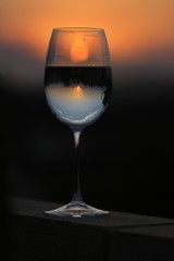 Reflection of the sun and sunset in a bright orange sky through a glass of wine. 