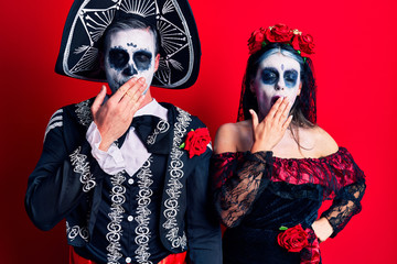 Young couple wearing mexican day of the dead costume over red bored yawning tired covering mouth with hand. restless and sleepiness.