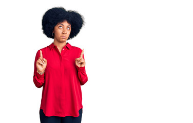 Young african american girl wearing casual clothes pointing up looking sad and upset, indicating direction with fingers, unhappy and depressed.