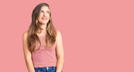 Obraz premium Beautiful caucasian young woman wearing casual clothes looking away to side with smile on face, natural expression. laughing confident.