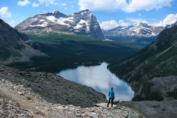 Trekker woman standing  on cliff above blue lakes in Yoho National Park. Lake O'Hara. British Columbia. Canada 