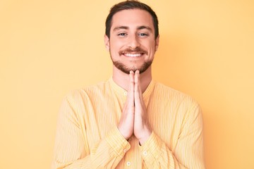 Young handsome man wearing casual clothes praying with hands together asking for forgiveness smiling confident.