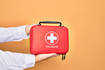 Hand of caucasian young woman holding first aid kit briefcase over isolated white background