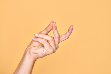 Hand of caucasian young man showing fingers over isolated yellow background snapping fingers for success, easy and click symbol gesture with hand