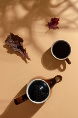 Autumn leaves pattern with coffee or tea cup on colored background. Flat lay.