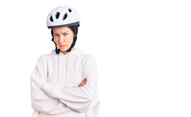 Beautiful brunette young woman wearing bike helmet and sporty clothes skeptic and nervous, disapproving expression on face with crossed arms. negative person.
