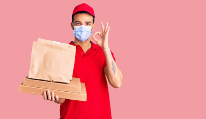 Young handsome hispanic man delivering food wearing covid-19 safety mask doing ok sign with fingers, smiling friendly gesturing excellent symbol