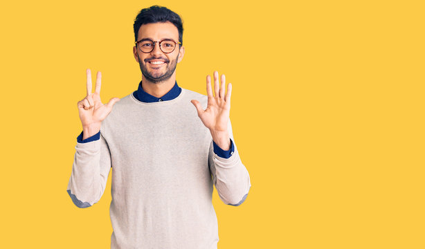 Young handsome hispanic man wearing elegant clothes and glasses showing and pointing up with fingers number eight while smiling confident and happy.