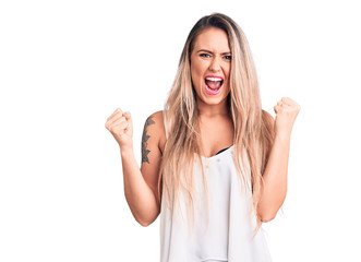 Young beautiful blonde woman wearing sleeveless t-shirt screaming proud, celebrating victory and...