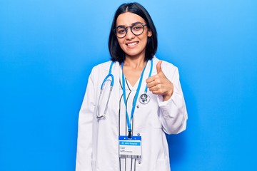 Young beautiful latin woman wearing doctor stethoscope and id card smiling happy and positive,...