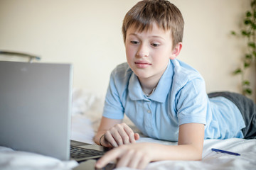 Distance learning online education. Schoolboy boy studies at home with laptop and does school homework.