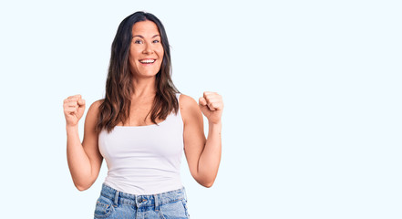 Fototapeta na wymiar Young beautiful brunette woman wearing casual sleeveless t-shirt celebrating surprised and amazed for success with arms raised and open eyes. winner concept.