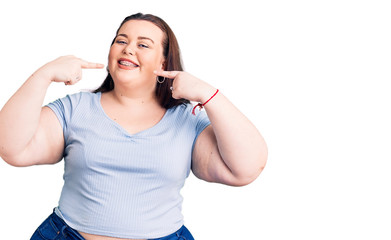 Young plus size woman wearing casual clothes smiling cheerful showing and pointing with fingers teeth and mouth. dental health concept.