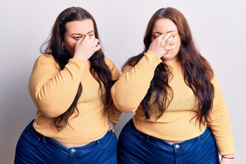 Young plus size twins wearing casual clothes tired rubbing nose and eyes feeling fatigue and headache. stress and frustration concept.