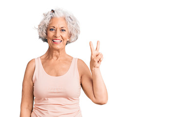 Senior grey-haired woman wearing casual clothes smiling with happy face winking at the camera doing victory sign. number two.