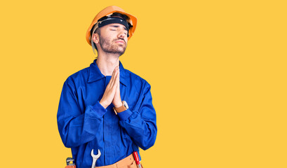 Young hispanic man wearing worker uniform begging and praying with hands together with hope expression on face very emotional and worried. begging.