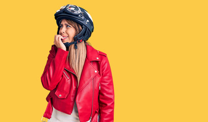 Young beautiful woman wearing motorcycle helmet looking stressed and nervous with hands on mouth biting nails. anxiety problem.