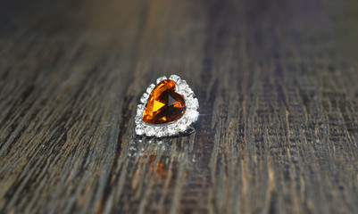 White gold necklace pendant A heart-shaped yellow gem on the wooden floor