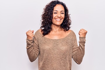 Middle age beautiful woman wearing casual sweater celebrating surprised and amazed for success with arms raised and eyes closed