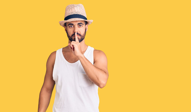 Young hispanic man wearing casual summer hat asking to be quiet with finger on lips. silence and secret concept.
