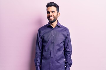 Young handsome man with beard wearing casual shirt looking away to side with smile on face, natural expression. laughing confident.