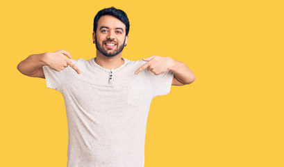 Young hispanic man wearing casual clothes looking confident with smile on face, pointing oneself with fingers proud and happy.