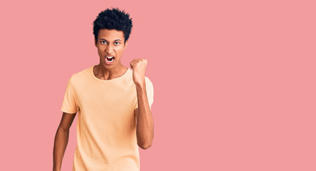 Young african american man wearing casual clothes angry and mad raising fist frustrated and furious...