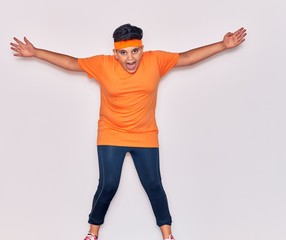 Adorable hispanic kid wearing sportswear smiling happy. Jumping with smile on face over isolated white background
