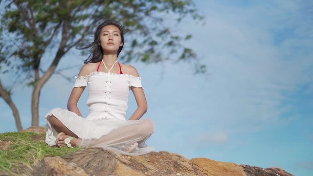 Slow motion clips,A beautiful woman practicing meditation on the rocks at the beach, Koh Samed in Thailand.