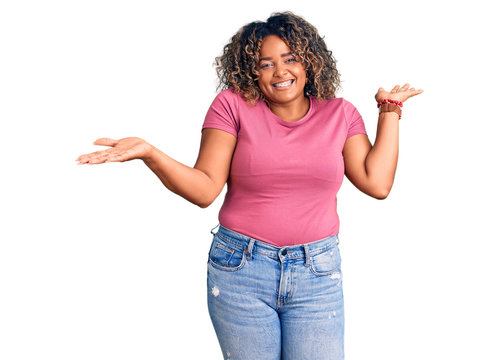 Young african american plus size woman wearing casual clothes clueless and confused expression with arms and hands raised. doubt concept.