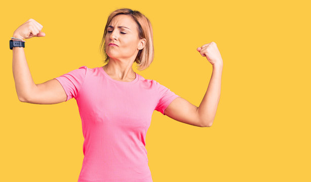 Young blonde woman wearing sportswear showing arms muscles smiling proud. fitness concept.