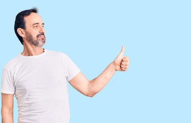 Fototapeta premium Middle age handsome man wearing casual t-shirt looking proud, smiling doing thumbs up gesture to the side